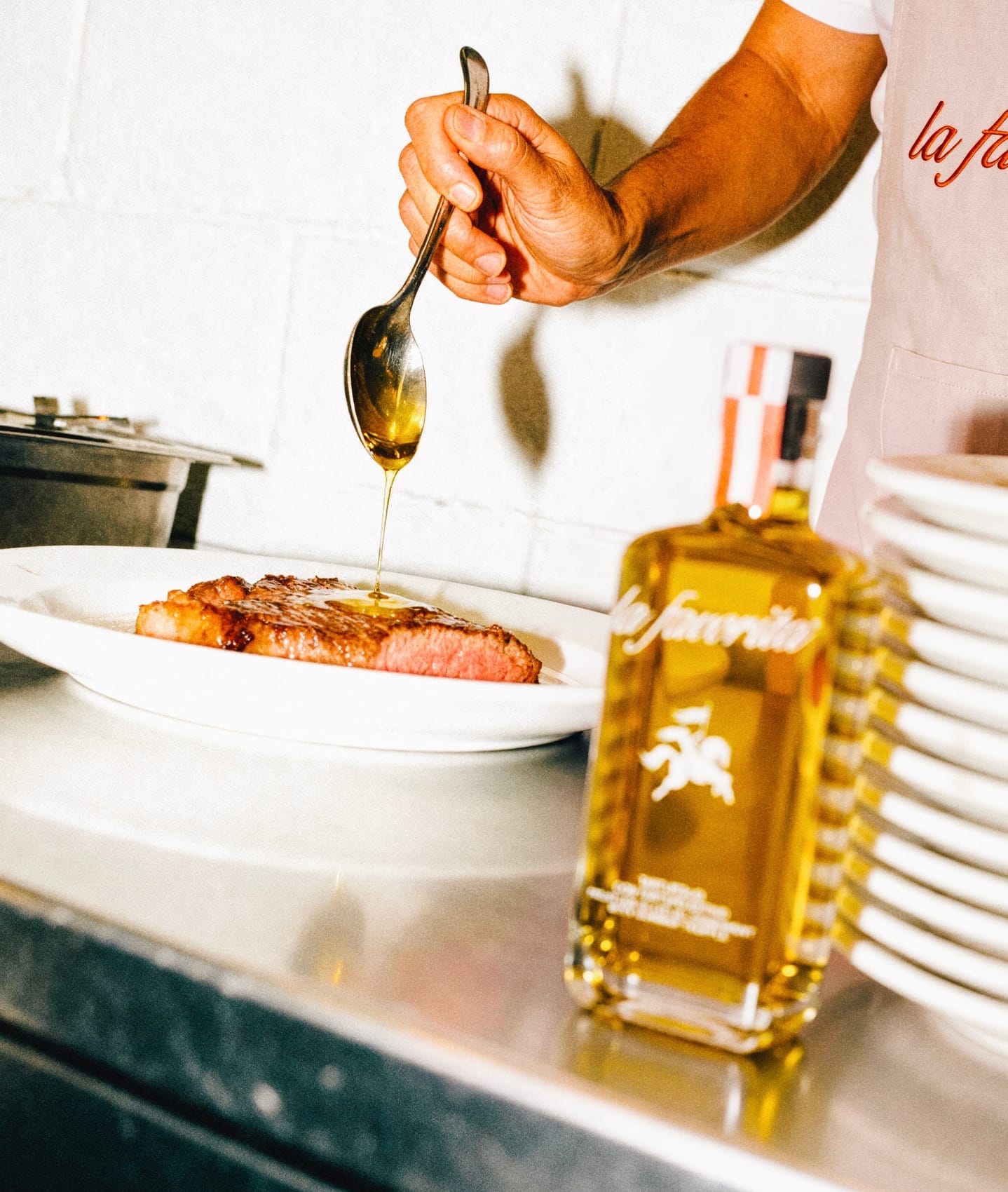 Un cuoco versa l'olio al tartufo su una bistecca accanto alla bottiglia La Favorita